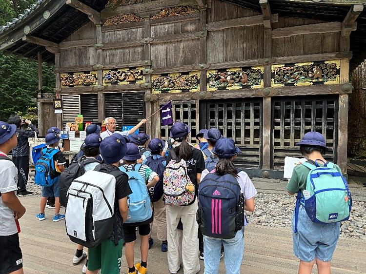 Student group in front of Toshogu Shrine entrance with guide gesturing toward architecture