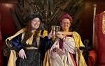 2 Students wearing medieval clothes sitting on throne and clinking chalices